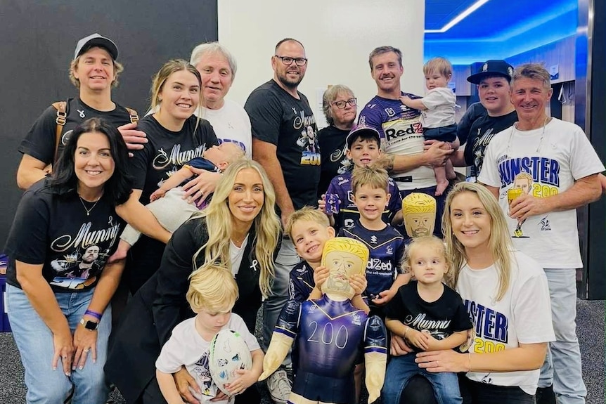 A group photo of a family celebrating in a footy dressing shed after a game.