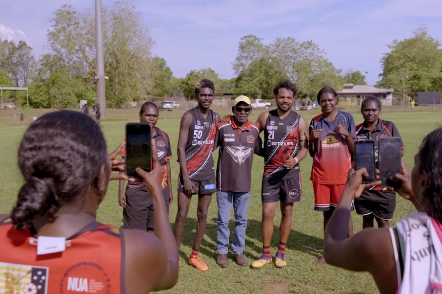 Willie Rioli taking a group photo on the field.