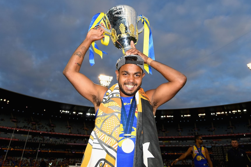 Willie Rioli Jr holds the AFL Premiership cup above his head.