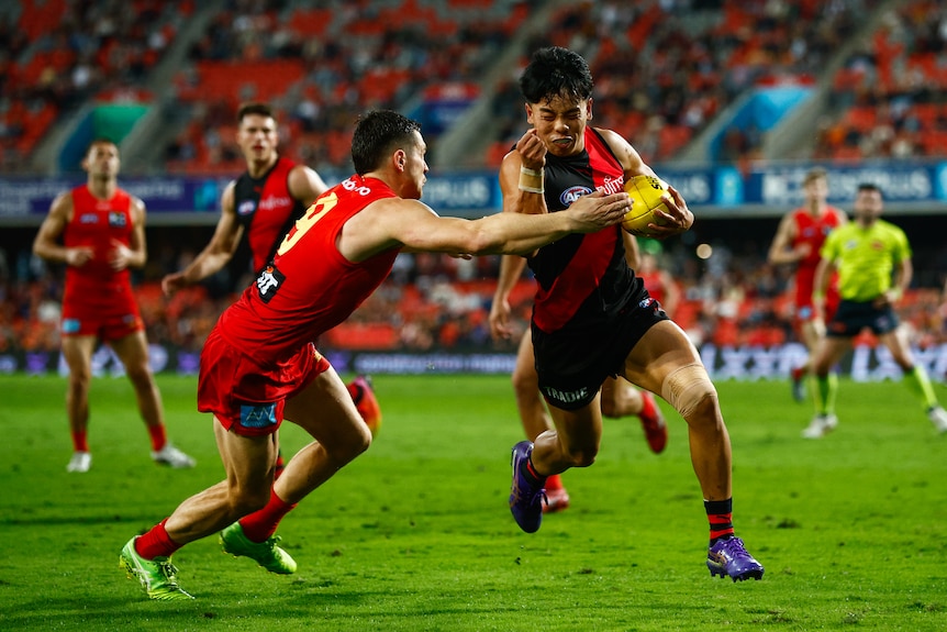 An AFL player tackled by another player during a match.
