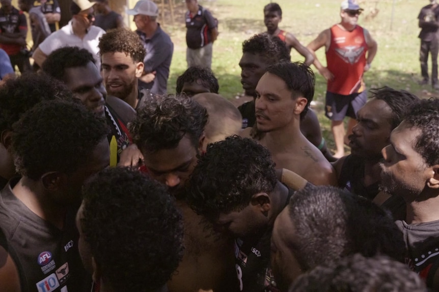 A group of football players huddling together.