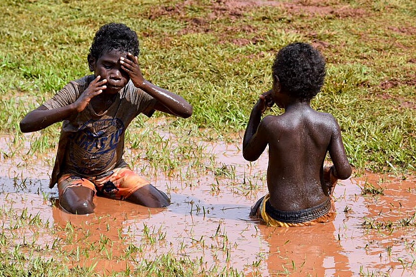 Two young children play in the grass on the Tiwi Islands.