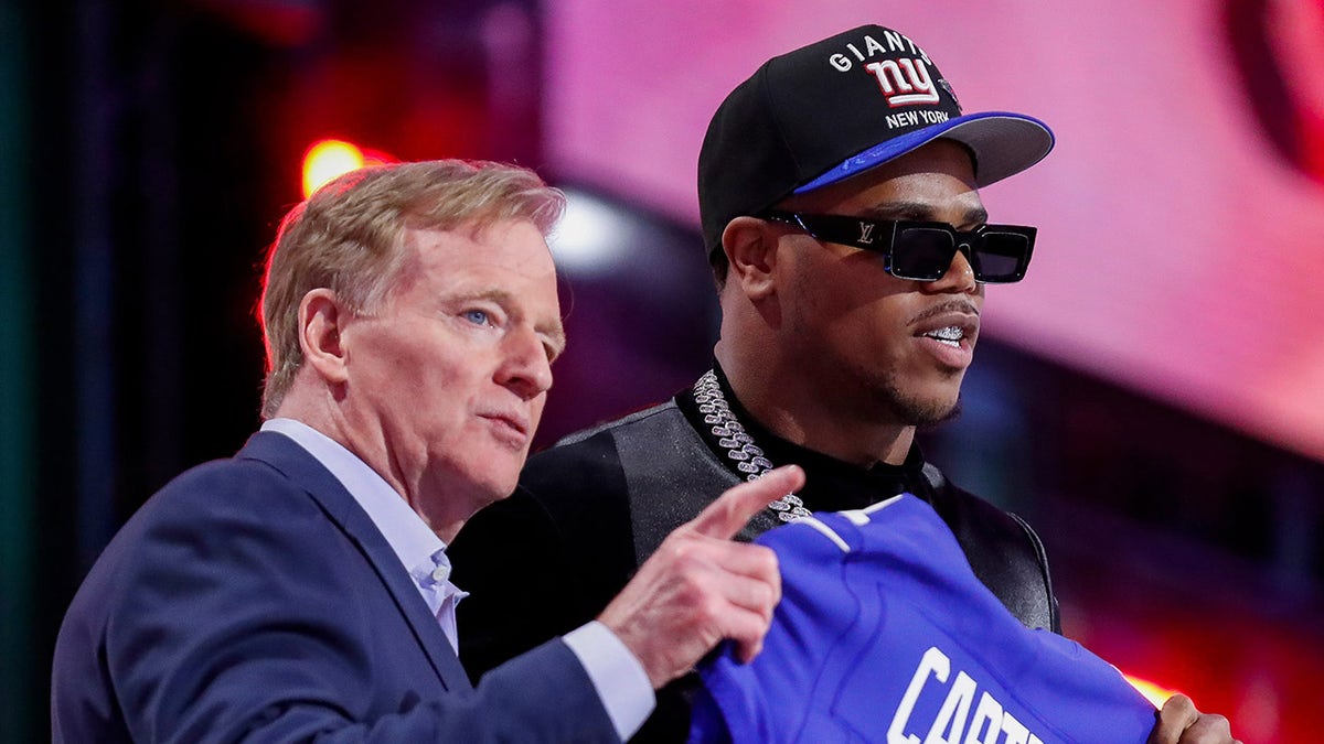 NFL Commissioner Roger Goodell pointing to New York Giants fans with Abdul Carter on stage at Lambeau Field
