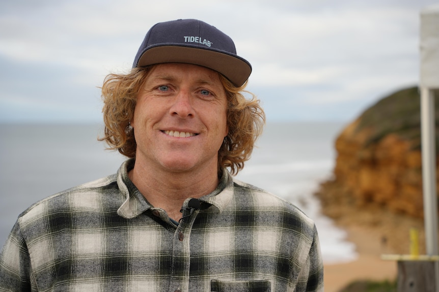 Surfing Victoria CEO Adam Robertson wears a cap and is smiling at Bells Beach